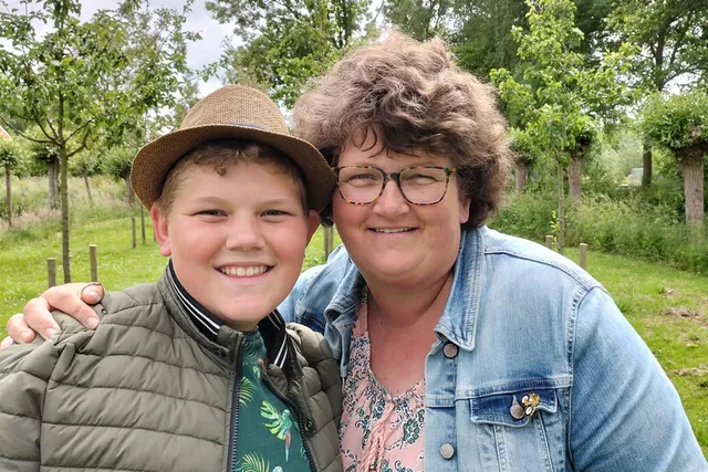 Op de foto staat Mathilda met een arm om de schouder van haar zoon, Jos. Jos draagt een hoedje en Mathilde draagt een bril.