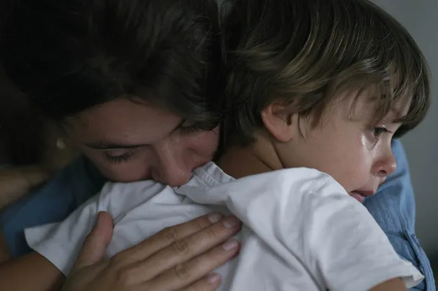 Stockfoto van moeder die haar jonge huilende zoon troost en omarmt.