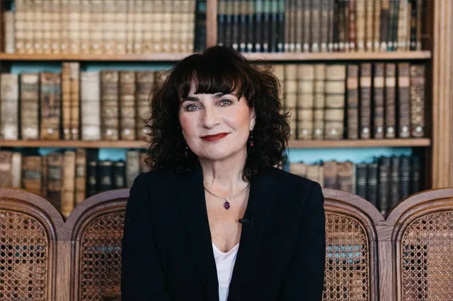 Anya Niewierra heeft donkerbruin kort haar tot haar schouders, met een pony boven haar ogen. Haar lippen zijn rood gestift en ze draagt een zwarte blazer. Ze zit voor een boekenkast vol oude boeken.