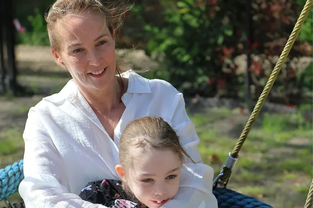 Pamela zit samen met haar dochter Robine op een schommel, Robine leunt op haar armen.
