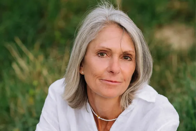 Anja woonde en werkte tien jaar in het klooster als non. Ze heeft een witte blouse aan en glimlacht in de camera.