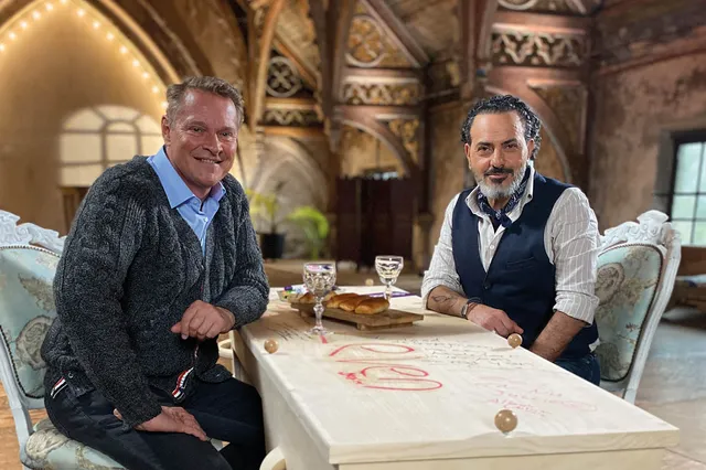 Albert Verlinde en Kefah Allush zitten samen bij de Kist. Ze lachen in de camera.