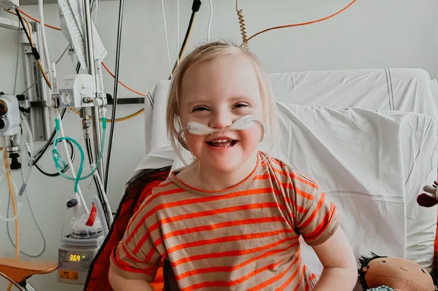 Livia, de dochter met downsyndroom, is de dochter van Mama Mirjam. Ze zijn in het ziekenhuis vanwege Livia, die te weinig zuurstof heeft. Op de foto lacht Livia in de camera met snoertjes om haar heen.
