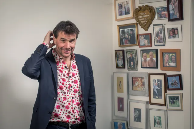 Ontwikkelingspsycholoog Steven Pont voor een muur met familiefoto's.