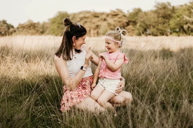 Everdien zit met haar dochter Jackie op schoot terwijl ze communiceren in gebarentaal en naar elkaar glimlachen.