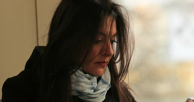 Een kort kerstverhaal door Marlies Medema. Vrouw met losse haren voor haar gezicht, een jas en een sjaal om.