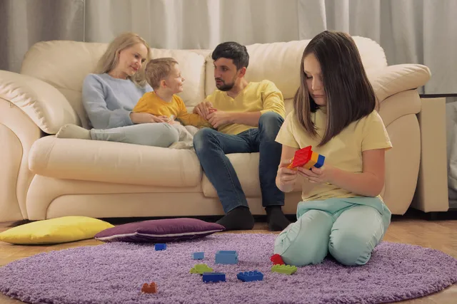 sibling relationship. Parents play with a younger child. The eldest child hurt. Jealousy in the family. Children's jealousy, resentment.