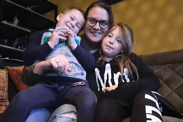 Cornelia met haar twee kinderen op de bank. Ze knuffelen en lachen in de camera.