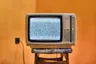 Tv met sneeuw op een krukje en een jaren 60 oranje behang