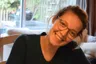 Op de foto staat Hilde lachend. Ze heeft een bril op en haar haar zit in een staart.